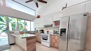 A modern kitchen with a central island, stainless steel appliances, and a view of the outdoors. - Charming 3-bedroom condo with pool, AC, WiFi in peaceful Herradura, pet friendly (Herradura)