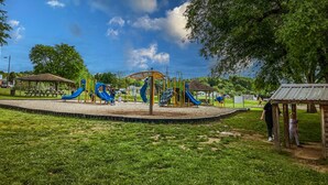 A playground with slides and climbing structures, surrounded by grass and trees. - Tranquil TN Escape! Book Your Stay In Elizabethton (Elizabethton)