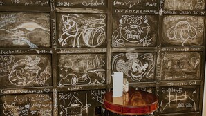A room with a wooden floor and a table with a vase. The walls are covered with chalkboard panels displaying various writings and drawings. - Tranquil TN Escape! Book Your Stay In Elizabethton (Elizabethton)