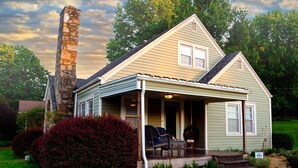 A two-story house with a stone chimney, a porch with outdoor furniture, and a well-maintained garden. - Tranquil TN Escape! Book Your Stay In Elizabethton (Elizabethton)