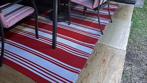 Et udendørs spiseområde med et bord, stole og en grill.