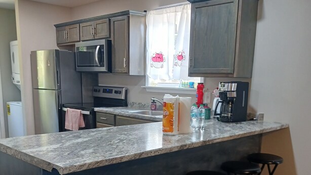 A kitchen with a granite countertop, stainless steel appliances, and bar stools. - Sweet Home 5 (Franklin)