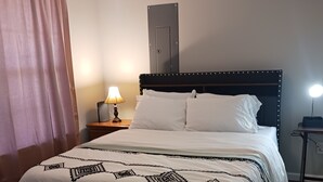 A neatly made bed with a patterned bedspread, a bedside lamp, and a nightstand with a lamp. - Sweet Home 5 (Franklin)