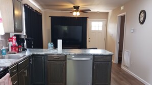A modern kitchen with dark wood cabinets, a built-in dishwasher, and a large island. - Sweet Home 5 (Franklin)