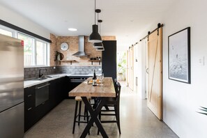 Una cucina moderna con isola centrale, mobili neri, una parete decorata con mattoni e un'ampia finestra.