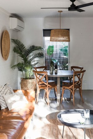 A modern living space with a dining area, a sofa, a coffee table, and a ceiling fan. - The Sunshine Bungalow Beautiful Noosa Home (Noosa)