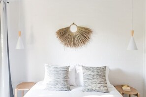 Ein Bett mit zwei gemusterten Kissen, einem an der Wand befestigten Dekoelement und zwei Pendelleuchten.