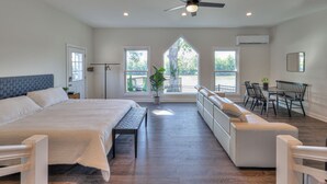 Une chambre spacieuse avec un grand lit, un banc, un canapé et un coin repas avec des chaises.