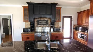 A modern kitchen with dark cabinetry, a central island with a sink, and built-in appliances including a stove, microwave, and oven.