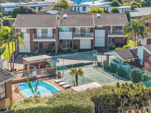A residential property with a swimming pool, tennis court, and multiple balconies. - Anchor Bell Apartments: (Sleeps 5) (Merimbula)