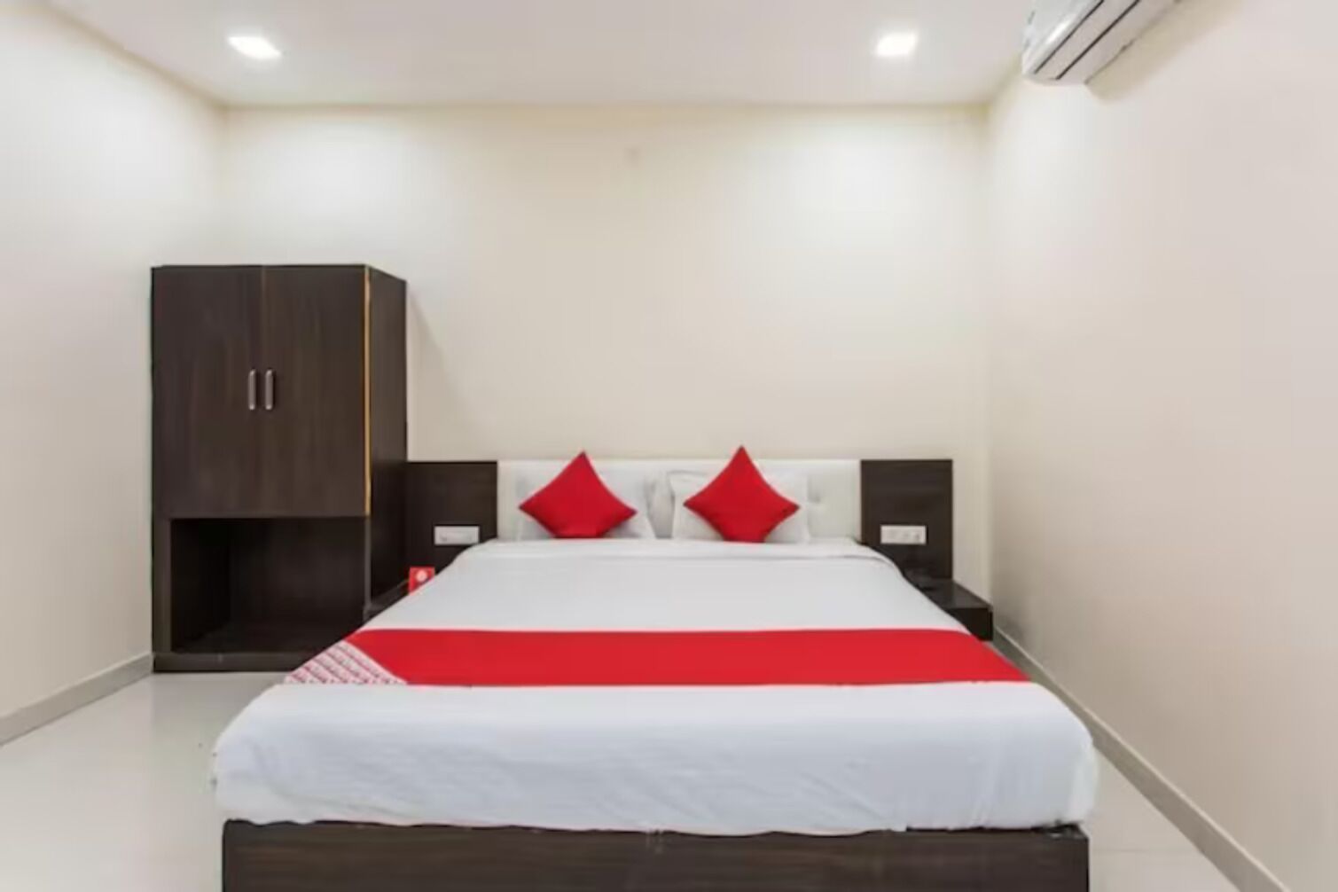 Una habitación de hotel con una cama, un armario y una mesita de noche.