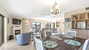 Amplia sala de estar con chimenea, una mesa de comedor con individuales y una cocina con armarios de madera.