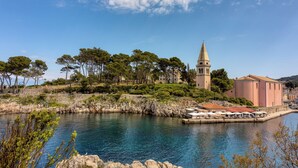 A coastal town with a prominent church tower, a waterfront area with outdoor seating, and a rocky shoreline.