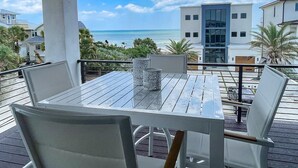 Un balcón con mesa y sillas, con vista a una playa y al océano.