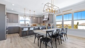 Una cocina moderna con una isla grande, taburetes de bar y una mesa de comedor con sillas.