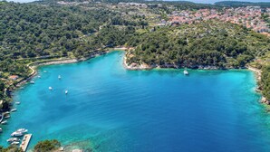 Vista aérea de un pueblo costero con una bahía, barcos y abundante vegetación.