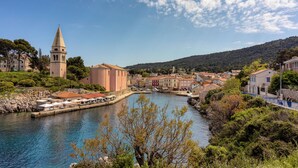 Un pueblo costero con una torre destacada, un río y una combinación de edificios tradicionales y modernos.