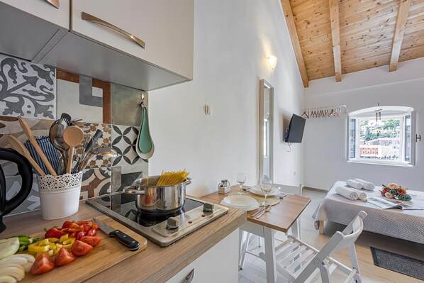 Une cuisine moderne équipée d’une cuisinière, d’une planche à découper et d’ustensiles de cuisine. On aperçoit également un coin repas avec une table et des chaises.