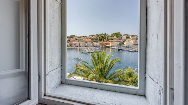 Vista desde una ventana a un pueblo costero con edificios y barcos.