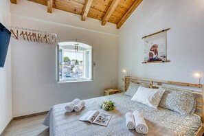 Ein Schlafzimmer mit Bett, Fenster mit Blick, einem Wandbild und Holzboden.