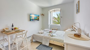 Une chambre à coucher avec un lit, un bureau et une chaise, une fenêtre et un tableau accroché au mur.