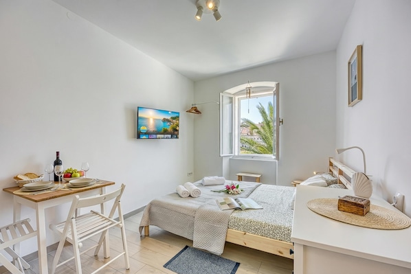 Une chambre à coucher avec un lit, un bureau et une chaise, une fenêtre et un tableau accroché au mur.