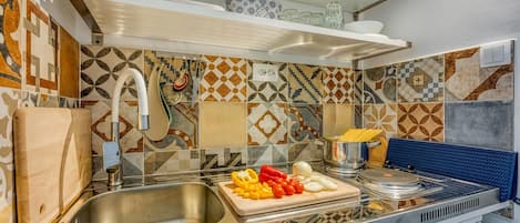 A kitchen with a sink, cutting board with vegetables, and a stove.