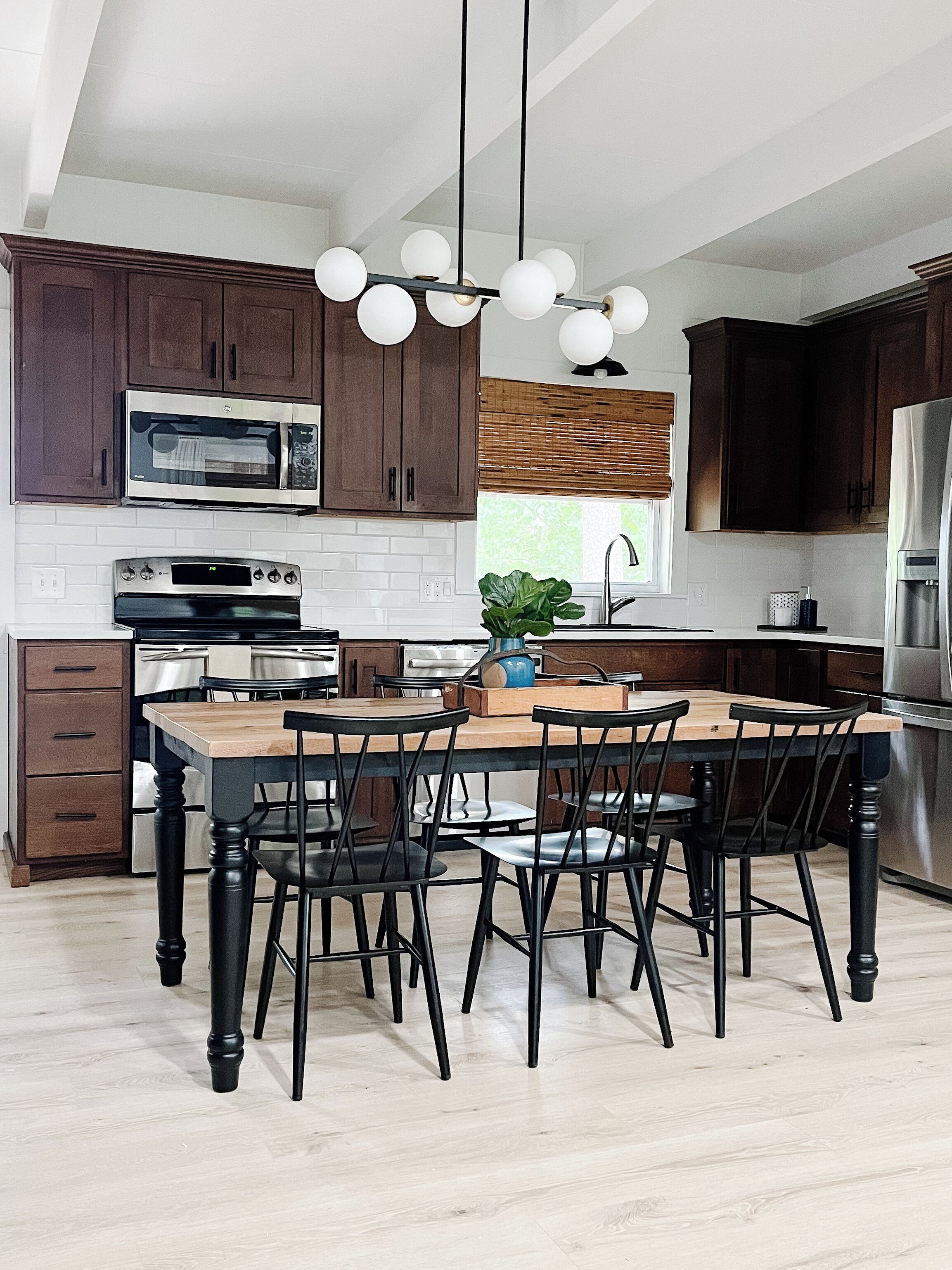 Une cuisine moderne avec des meubles en bois foncé, des appareils électroménagers en acier inoxydable et un îlot central doté de chaises.