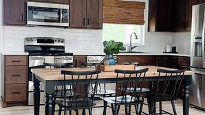 Una cocina moderna con armarios de madera oscura, electrodomésticos de acero inoxidable y una isla central con sillas.
