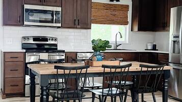 Une cuisine moderne avec des meubles en bois foncé, des appareils électroménagers en acier inoxydable et un îlot central doté de chaises.