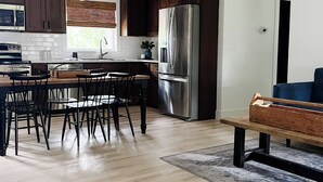 Una cocina moderna con armarios de madera oscura, electrodomésticos de acero inoxidable y una zona de comedor con banco y sillas de madera.