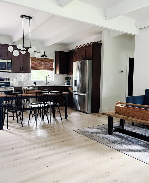 A modern kitchen with dark wooden cabinets, stainless steel appliances, and a dining area with a wooden bench and chairs. - Newly Remodeled 3-bedroom house with Amazing Views of the Lake! (Camdenton)
