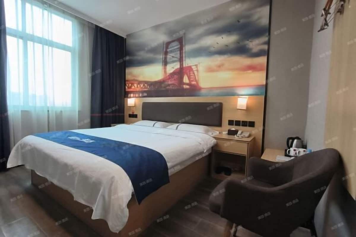 Quarto de hotel com cama, mesa de cabeceira, cadeira e um mural de uma ponte.