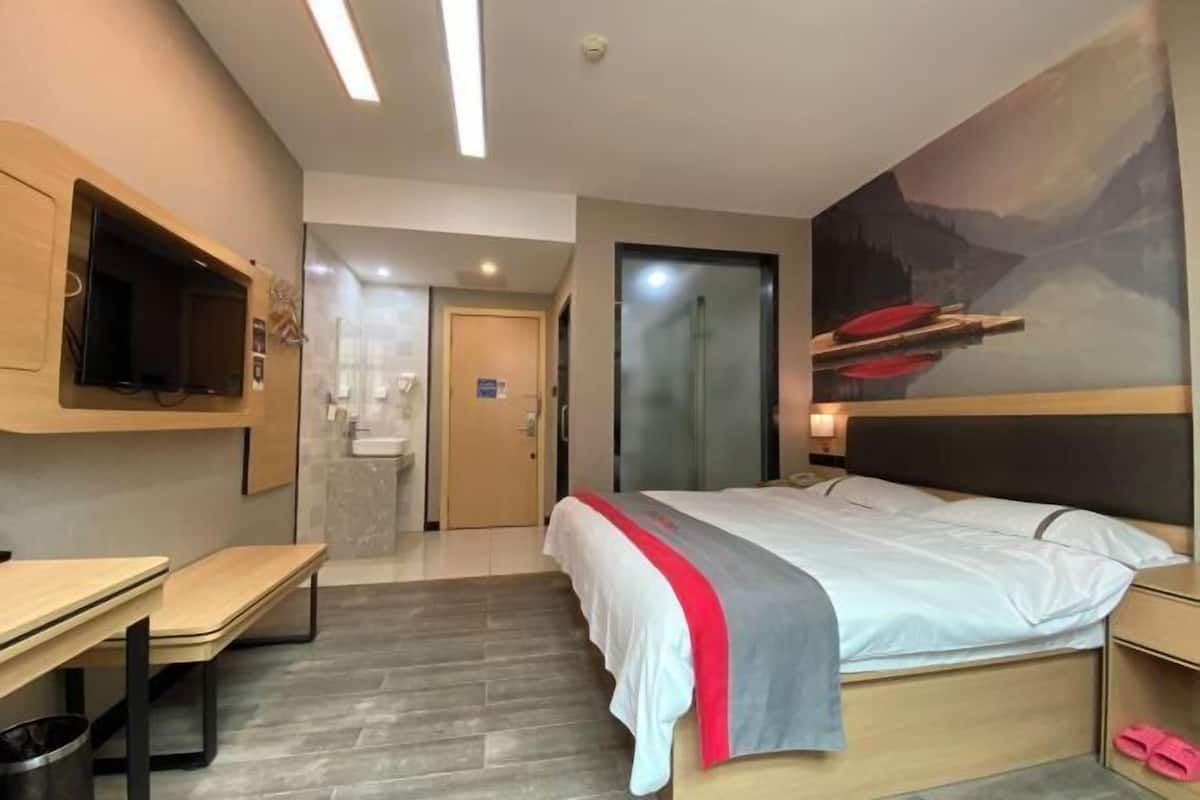Quarto de hotel moderno com cama, escrivaninha, televisão e banheiro.
