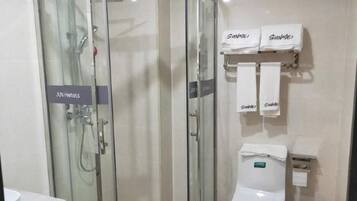 A bathroom with a glass-enclosed shower, a toilet, and two towels hanging on a rack.
