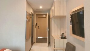 A narrow hallway with a door at the end, a coat rack, and a small table with a kettle. - Dongguan Haiyi Chain Hotel (Dongguan)