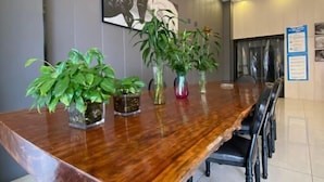 A conference table with four potted plants, a framed artwork on the wall, and a bulletin board with papers. - Dongguan Haiyi Chain Hotel (Dongguan)