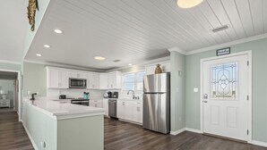 Una cocina moderna con armarios blancos, electrodomésticos de acero inoxidable y una isla central.