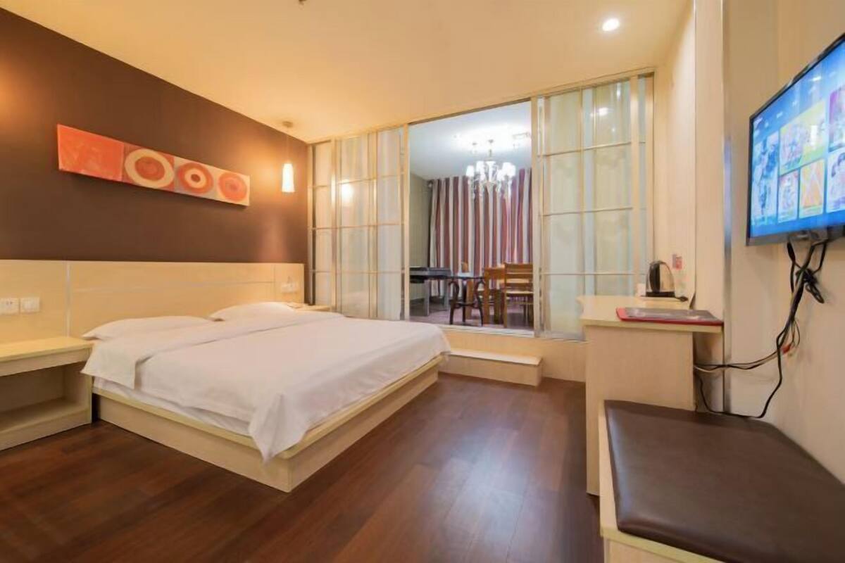 A hotel room with a bed, a desk, a chair, and a TV.