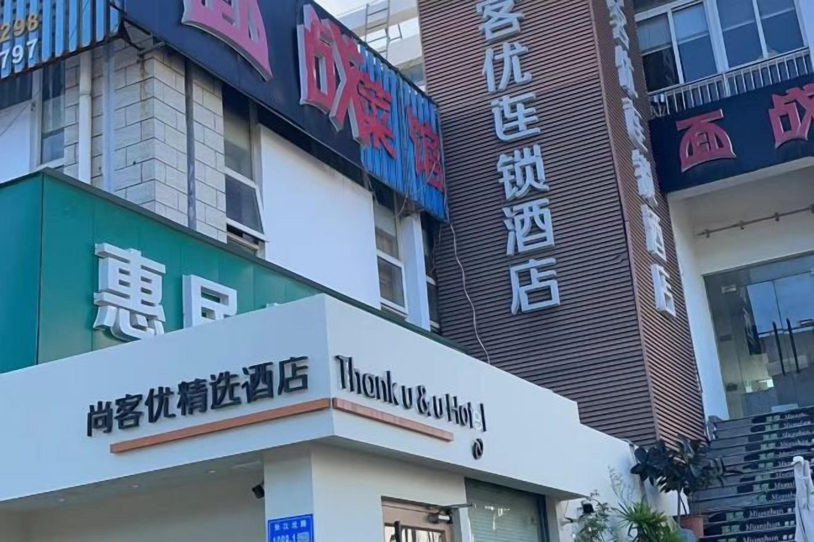 A building with multiple signs, including one for a hotel and another for a store.