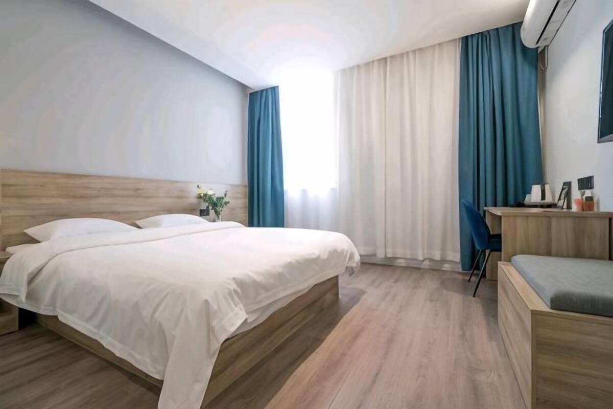 A hotel room with a bed, a desk, and a chair.