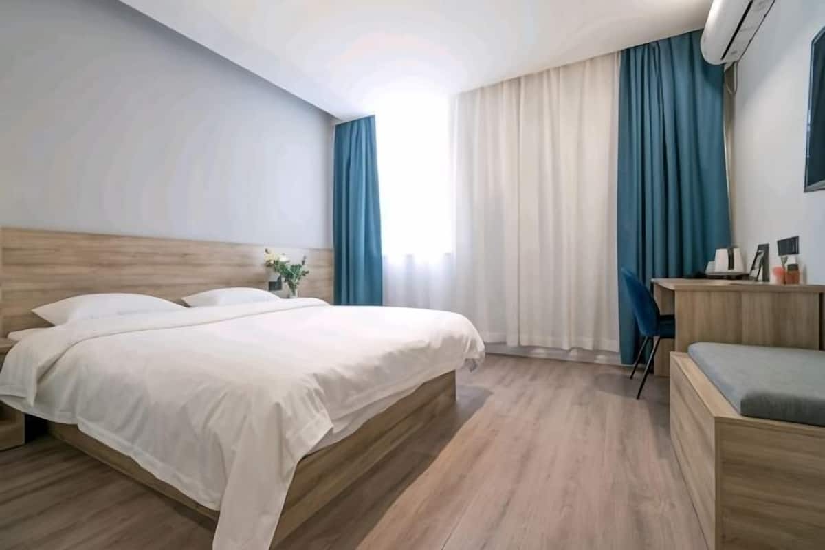 A hotel room with a bed, a desk, and a chair.