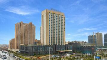 A high-rise hotel with multiple floors, a modern design, and a parking area in front.