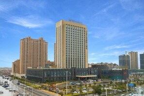 A high-rise hotel with multiple floors, a modern design, and a parking area in front. - Xinghewan International Hotel (Sheyang)