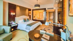 Habitación de hotel con una cama grande, mesitas de noche, un escritorio, una silla, una lámpara y un espejo.