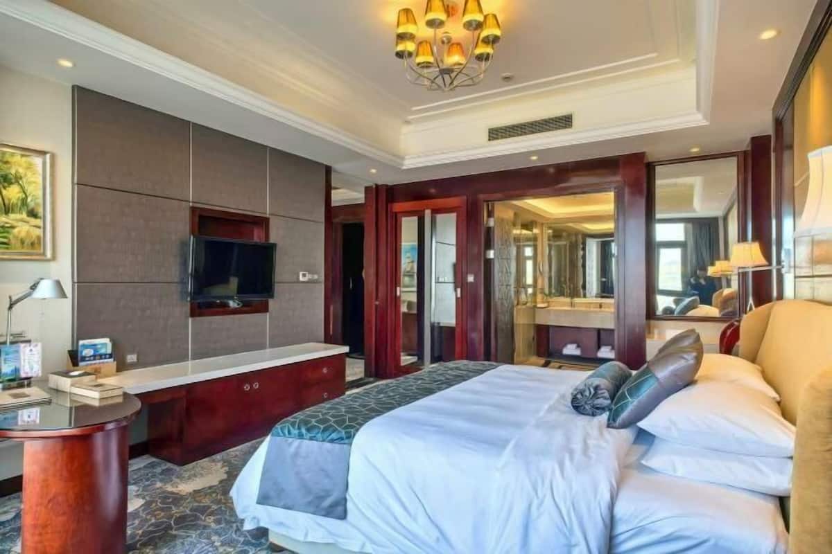 A hotel room with a bed, a TV, a desk, and a mirror.