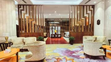 A lobby with a central reception desk, two sofas, and a patterned carpet.