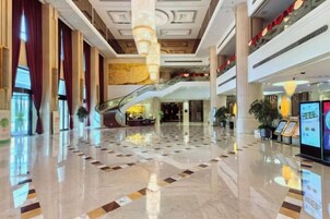 Un hall amplio con piso de mármol pulido, una columna central y una escalera mecánica que lleva a otro nivel.