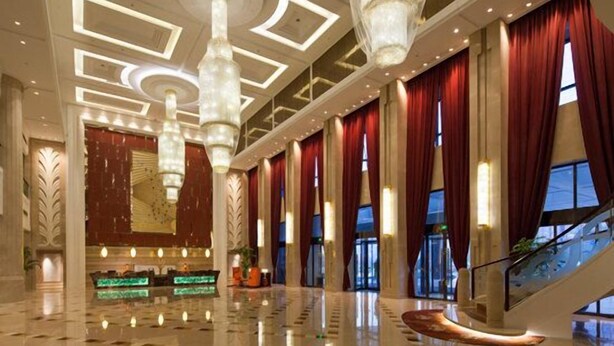 Un lobby espacioso con un techo alto, grandes candelabros y una imponente escalera.