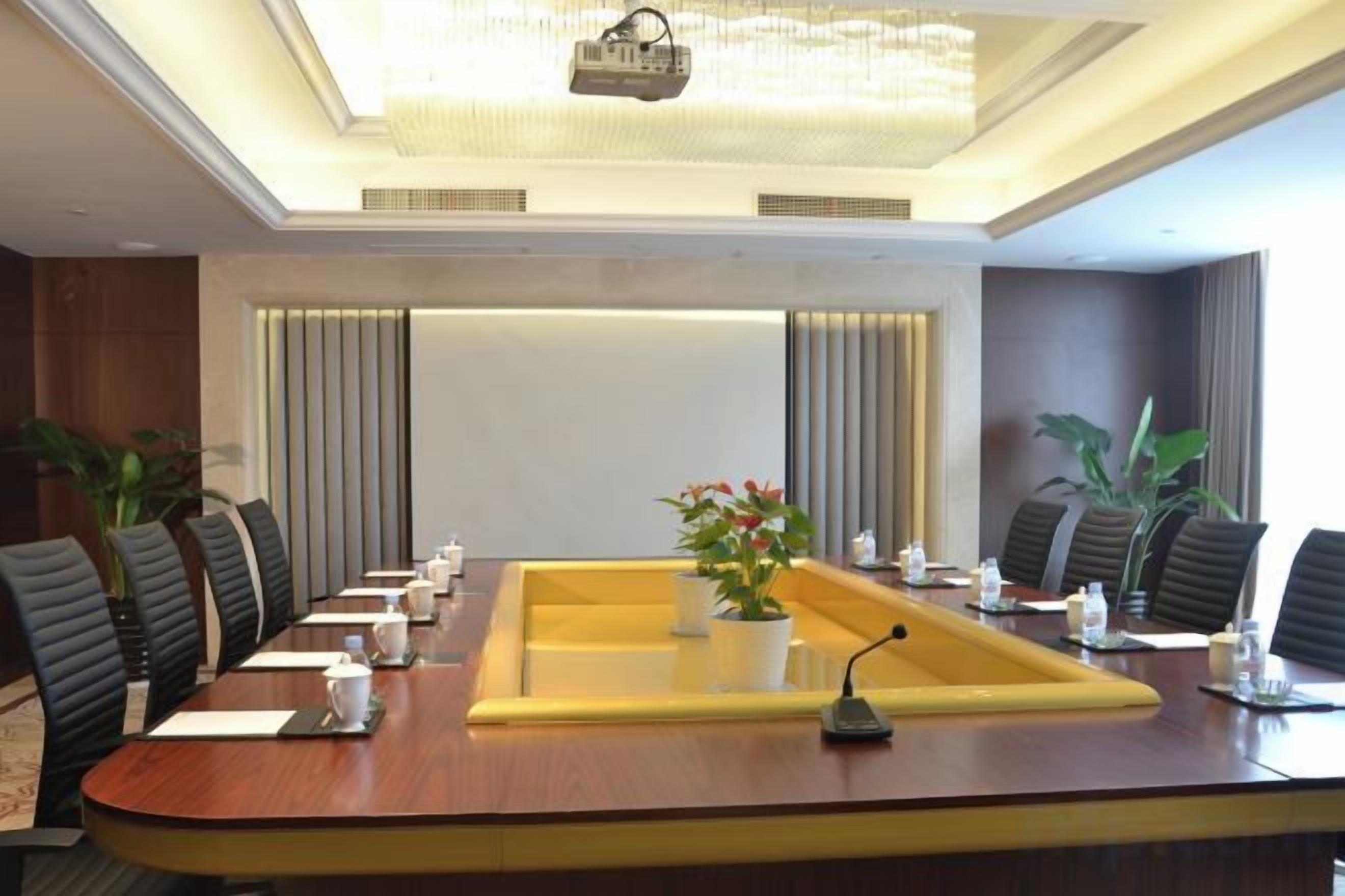 A conference room with a long table, chairs, and a projector.